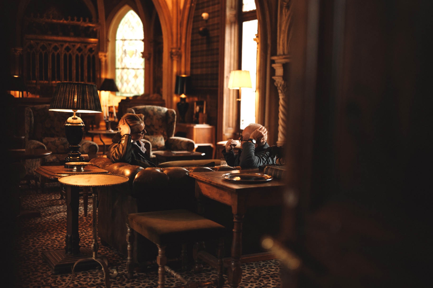 Odyssey guests in conversation in a warmly lit gothic lounge.